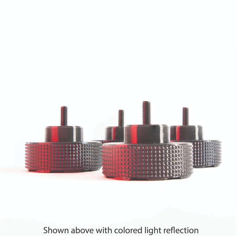 SpinCandy isolation feet under red ambient lighting, showing subtle gloss and light-catching faceted surfaces. Styled for DJ and home audio environments with accent lighting.